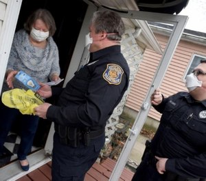 Luna Pier Police Reserve Officers Keith Blosser and Kenneth Mentel delivers Rosanne Metcalf her prescription medicine and light bulbs.