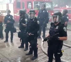 Police officers respond to a fire and unruly crowd at the scene of a sex trafficking investigation.