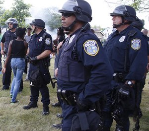 A young girl walks between police in a park in Milwaukee, Monday, Aug. 15, 2016.