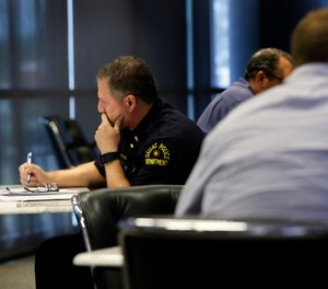 In this June 22, 2017, photo, Dallas police Lt. Michael Igo, left, contemplates his response to a task as he and fellow officers participate in a training session at the Center for Brain Health in Dallas. Only hours after the ambush that killed five Dallas law enforcement officers July 7, 2016, mental health experts began thinking ahead, searching for ways to ease the long-term effects of the attack on the men and women who patrol the nation’s ninth-largest city. Scores of them have received or are on track to receive specialized training in “mindfulness” and other stress-management techniques.