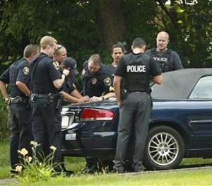 Police officers confer in the driveway of a home in Mendota Heights, Minn., Wednesday afternoon, July 30, 2014.
