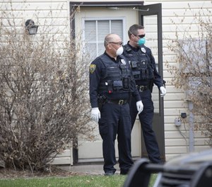 Two Brooklyn Park police officers stand outside a home during a welfare check. Minneapolis police Chief Medaria Arradondo said Monday that all officers will be expected to wear protective masks after the department saw its first case of COVID-19. (Photo/TNS)