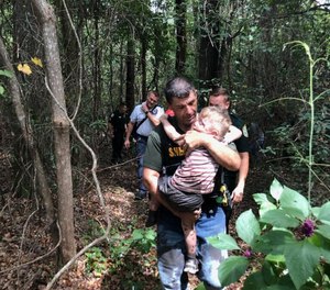 Santa Rosa County Sheriff's Office Deputy Robert Lenzo carries three-year-old Aedric Hughes, who deputies recovered with the help of tracking bloodhounds.