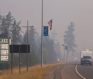 A pickup truck pulls a camper through the wildfire smoke in Seeley Lake in Missoula County, Mont. (Kari Greer/U.S. Forest Service via AP)
