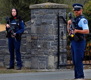 Police officer, left, stands guard with a rose on her chest to pay respect at the burial service for a victim of the Friday March 15 mosque shootings