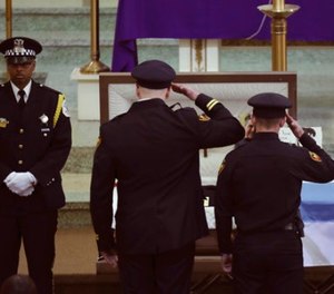Two officers salute Chicago police Commander Paul Bauer before his funeral mass at Nativity of Our Lord Roman Catholic Church Saturday, Feb. 17, 2017, in Chicago.
