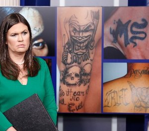 White House press secretary Sarah Huckabee Sanders stands in front of pictures of MS-13 gang tattoos during a press briefing at the White House in Washington, Thursday, July 27, 2017.