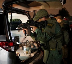 An ATF agent checks his weapon as he gets ready for a raid Wednesday morning, May 17, 2017, in Los Angeles. (AP Photo/Jae C. Hong)