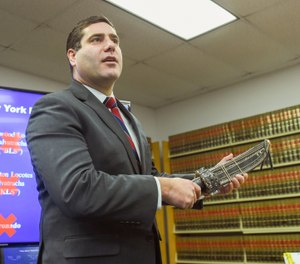 Suffolk County District Attorney Timothy Sini holds a machete while announcing an indictment of nearly 100 MS-13 gang members and associates during a news conference at Suffolk County Court in Riverhead, N.Y., Friday, Dec. 20, 2019. (James Carbone/Newsday via AP)