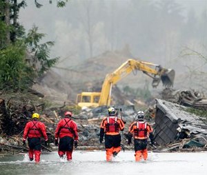 Four search and rescue workers wade through water of the massive mudslide that struck Oso, Wash. on March 22, 2014, killing 43 people. (AP Photo/Ted S. Warren, Pool)
