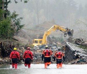 Four search and rescue workers wade through water of the massive mudslide that struck Oso, Wash. on March 22, 2014, killing 43 people. (AP Photo/Ted S. Warren, Pool)