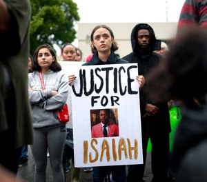 A protester holds a sign at the Edmond Police Department during a protest rally honoring the life of Isaiah Lewis, who was fatally shot in April.