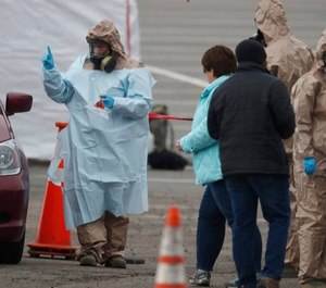 Colorado National Guard medical personnel perform coronavirus tests on a motorist at a drive-through testing site outside the Denver Coliseum.