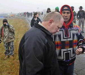 In this Oct. 26, 2016 file photo, Morton County Sheriff Kyle Kirchmeier, front, listens to Brian Wesley Horinek, of Oklahoma, outside the New Camp on Pipeline Easement in North Dakota. (Tom Stromme/The Bismarck Tribune via AP File)