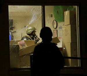 Police check a store after tear gas was used to disperse a crowd Sunday, Aug. 17, 2014, during a protest for Michael Brown, who was killed by a police officer last Saturday in Ferguson, Mo. (AP Image)