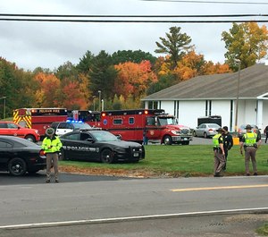 In this photo provided by WMUR-TV, police stand outside the New England Pentecostal Church after reports of a shooting on Saturday, Oct. 12, 2019, in Pelham, N.H. (Siobhan Lopez/WMUR-TV via AP)