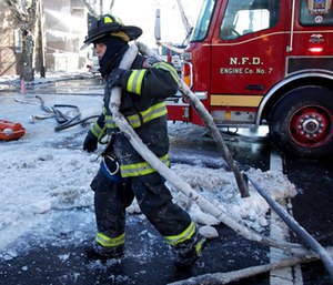 A Newark firefighter pulls a hose back onto an engine after helping battle a five building fire in Newark, N.J.