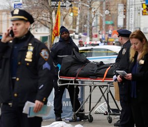 Police remove the body of a man following an incident in the Queens borough of New York. (AP Photo/Mark Lennihan)