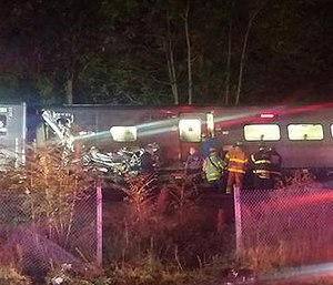 In this photo provided by Sarah Qamar rescue personnel look at a Long Island Railroad train that derailed near New Hyde Park, N.Y., Saturday, Oct. 8, 2016.