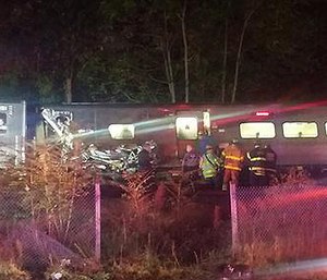 In this photo provided by Sarah Qamar rescue personnel look at a Long Island Railroad train that derailed near New Hyde Park, N.Y., Saturday, Oct. 8, 2016.