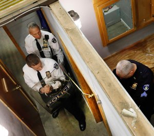 New York City Police Dept. Chief Robert Lukach, background center, and Capt. Ronald Zedalis, left, negotiate with Sgt. Kenneth O'Brien portraying a barricaded person during a tactical demonstration at New York City Emergency Service Unit headquarters at Floyd Bennett Field in New York, on Thursday, March 28, 2019. (AP Photo/Richard Drew)