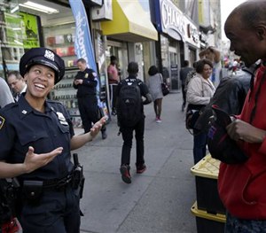 In this April 29, 2015 photo, police officer Lanora Moore talks with a man on 125th Street in Harlem.
