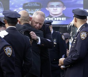A couple of police officers embrace as they arrive for the funeral mass of New York City police officer Brian Moore, Friday, May 8, 2015.