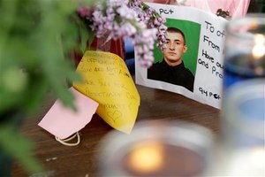 A picture of Brian Moore is displayed amongst flowers and candles at a memorial in front of his precinct house in the Queens section of New York, Tuesday, May 5, 2015.