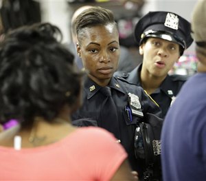 Police officers Shakara President, center, and Lanora Moore talk with an unhappy customer inside a store on 125th Street in the Harlem section of New York, Wednesday, April 29, 2015.