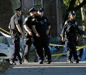 Emergency personnel walk near the scene of a fatal shooting of a New York City police officer in the Bronx borough of New York, Sunday, Sept. 29, 2019.