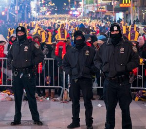 NYPD officers stand near revelers gathered on Times Square in New York on December 31, 2018. The NYPD will use drones and cameras for added security.