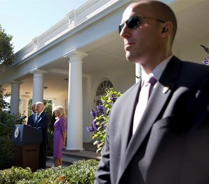 A Secret Service Agent stands guard as then-Vice President Joe Biden, with President Barack Obama and his wife Jill Biden, speaks in the Rose Garden of the White House on Oct. 21, 2015.