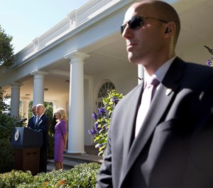 A Secret Service Agent stands guard as then-Vice President Joe Biden, with President Barack Obama and his wife Jill Biden, speaks in the Rose Garden of the White House on Oct. 21, 2015.