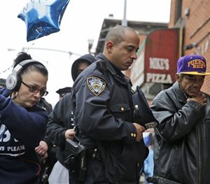 People, including a police officer, pay their respects at an impromptu memorial near the site where two police officers were killed in the Brooklyn borough of New York, Sunday, Dec. 21, 2014.