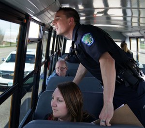 Eagan police officer Luke Nelson strained to get a better look at an offender as he and fellow officers rode a school bus looking for distracted driversduring Wednesday’s “Busted by the Bus” initiative. (Photo / MCT)