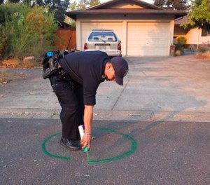Oakland Police officer Anh Nguyen spray paints the street to mark that a house in Calistoga, Calif., is vacant on Wednesday, Oct. 11, 2017.