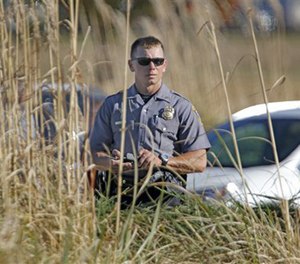 An Oklahoma City police officer looks through tall grass at a checkpoint at Will Rogers World Airport, Tuesday, Nov. 15 2016, in Oklahoma City.