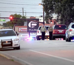 Police cars surround the Pulse Orlando nightclub, the scene of a fatal shooting, in Orlando, Fla., Sunday, June 12, 2016.