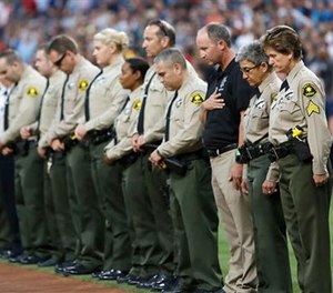 San Diego County Sheriff's Department officers stand in memory of officer Jonathan DeGuzman with a moment of silence before a baseball game between the Cincinnati Reds and the San Diego Padres on Friday, July 29, 2016, in San Diego.
