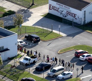 Students are evacuated by police from Marjory Stoneman Douglas High School in Parkland, Fla., on Wednesday, Feb. 14, 2018, after a shooter opened fire on the campus.
