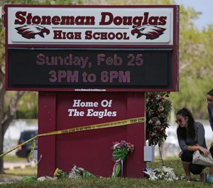 Mourners bring flowers as they pay tribute at a memorial for the victims of the shooting at Marjory Stoneman Douglas High School on Sunday, Feb. 25, 2018 during an open house as parents and students returned to the school for the first time since 17 people were killed in a mass shooting at the school in Parkland on Feb. 14, 2018. (David Santiago/Miami Herald/TNS)