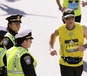 In this April 18, 2016 file photo, actor Mark Wahlberg, center left, dressed as a Boston Police officer, watches runners cross the finish line as he films a scene for the 