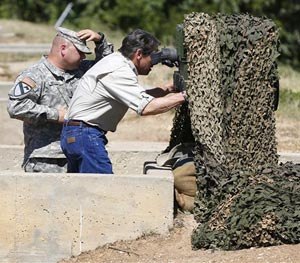 Gov. Rick Perry examines an advanced optics system at Camp Swift in Bastrop, Texas on Wednesday, Aug. 13, 2014. (AP Image)