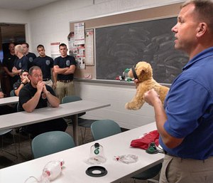 EMS crew listen to Roger Bell during a training session Friday, in which he described how to use an oxygen masks to revive pets.