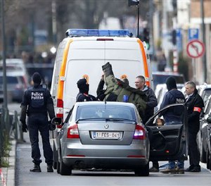 A member of emergency services puts on protective clothing to investigate the scene in Schaerbeek, Belgium, Friday March 25, 2016. (AP Image)