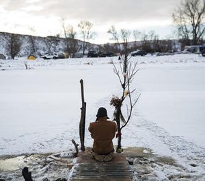 Army veteran Nick Biernacki, of Indiana, prays at the Cannonball River at the Oceti Sakowin camp where people have gathered to protest the Dakota Access oil pipeline in Cannon Ball, N.D., Sunday, Dec. 4, 2016.
