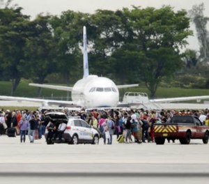 People stand on the tarmac at the Fort Lauderdale-Hollywood International Airport after a shooter opened fire inside a terminal of the airport, killing several people and wounding others before being taken into custody, Friday, Jan. 6, 2017, in Fort Lauderdale, Fla. (AP Photo/Lynne Sladky)