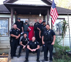 South Salt Lake police officers pose with 73-year-old Lejune Timmerman after replacing the American flag she used to defend her family from an intruder.
