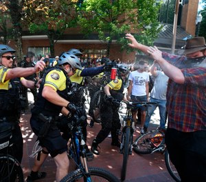 After a confrontation between authorities and protestors, police use pepper spray as multiple groups, including Rose City Antifa, the Proud Boys and others protest in downtown Portland, Ore., on Saturday, June 29, 2019. (Dave Killen/The Oregonian via AP)
