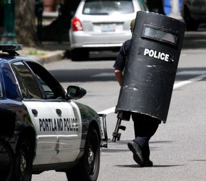 A Portland police officer heads down the street while looking for a man who is alleged to have pulled a handgun on a Portland State University security officer in Portland, Ore., Monday, June 11, 2012.